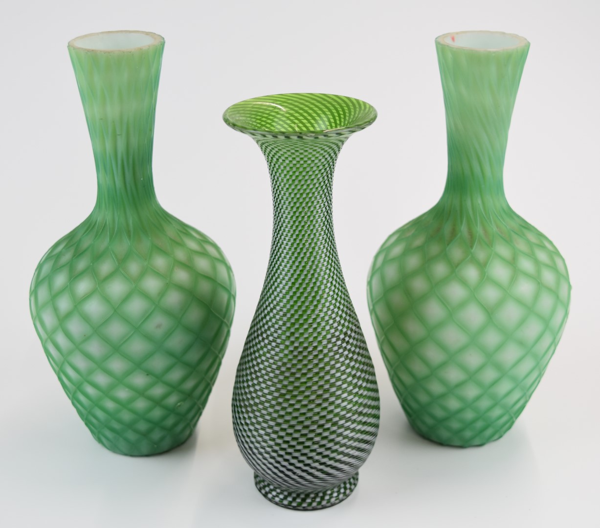 Three Stourbridge glass vases comprising a pair of quilted air trap satin bottles vases (21.5cm