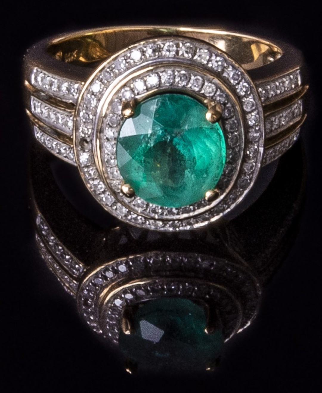 A 14k gold ring set with an oval cut emerald of approximately 1.8ct  surrounded by diamonds, 4.4g,