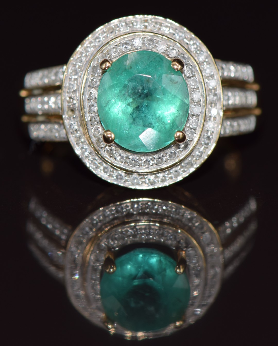 A 14k gold ring set with an oval cut emerald of approximately 1.8ct  surrounded by diamonds, 4.4g, - Image 2 of 3