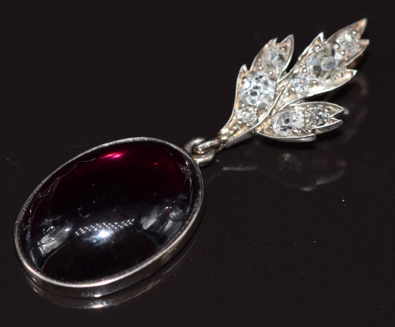 Victorian 9ct gold pendant set with a garnet cabochon and old cut diamonds in a foliate setting, the