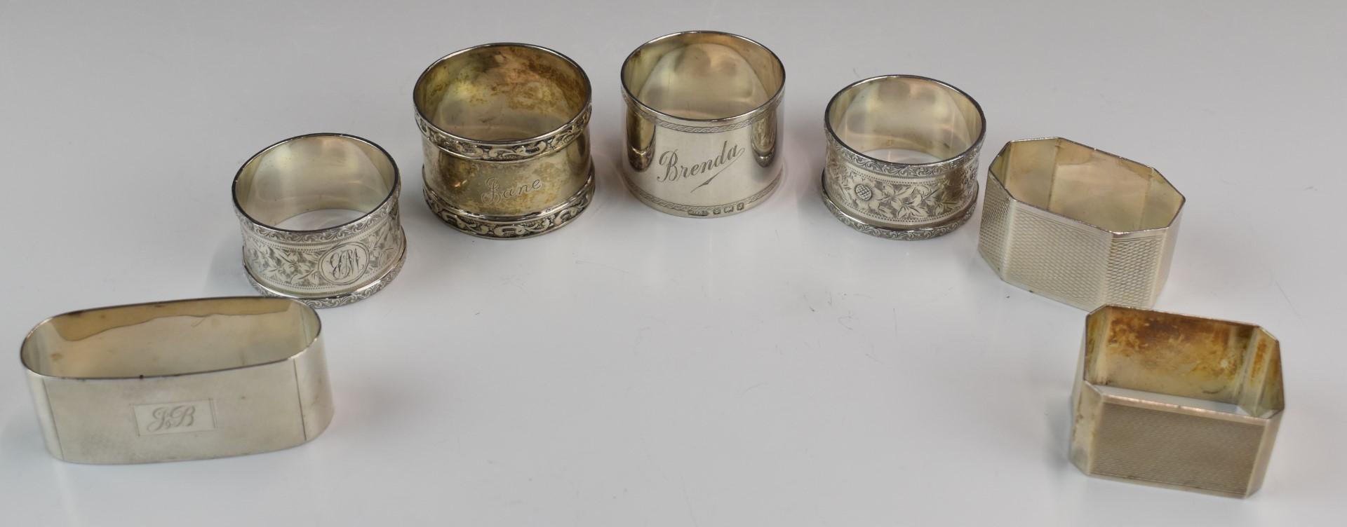 Seven various hallmarked silver napkin rings including a pair of Art Deco style engine turned