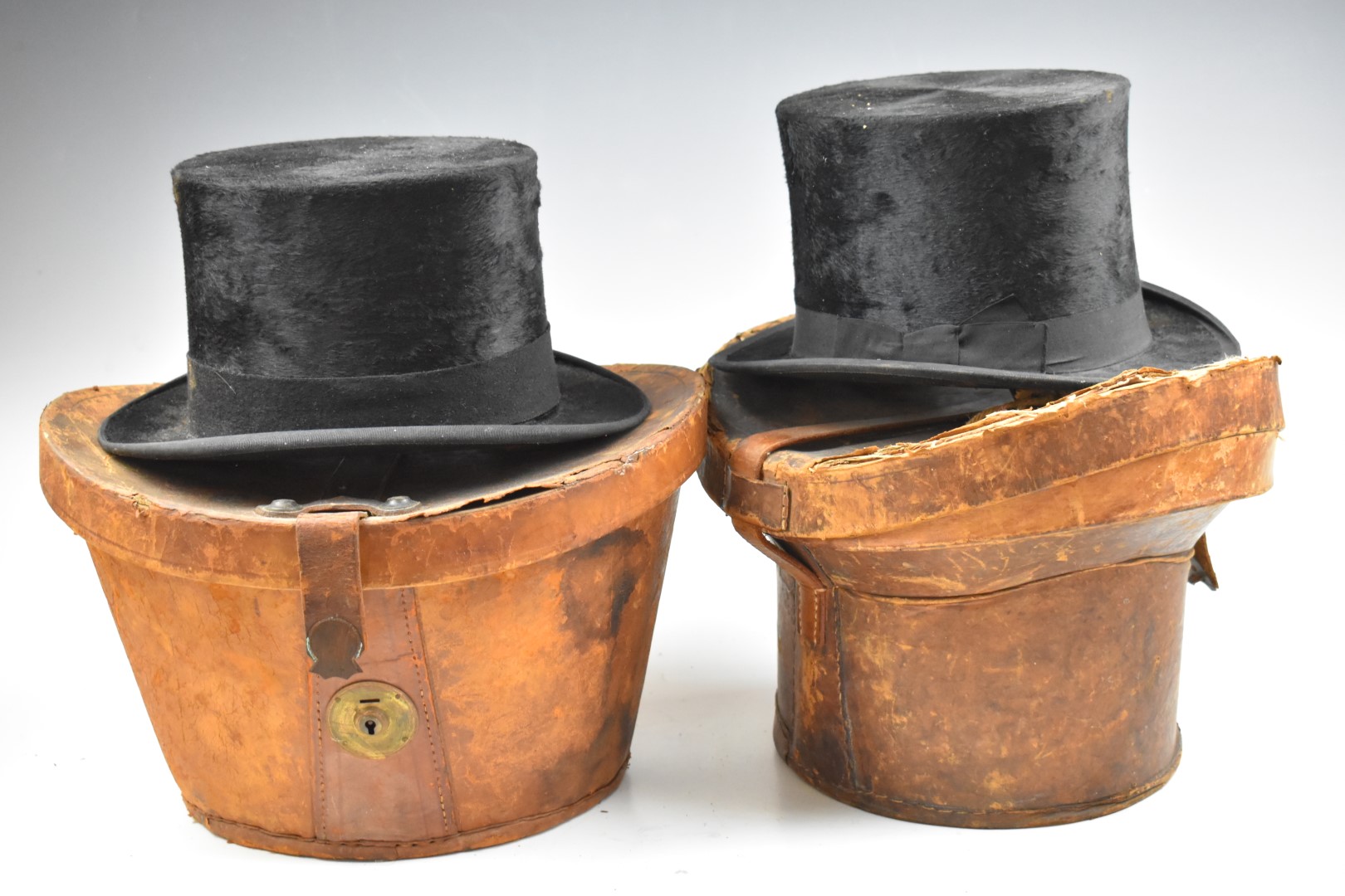 Two vintage top hats in leather cases, one Dunn & Co., London the other 'W' make Stockport, both