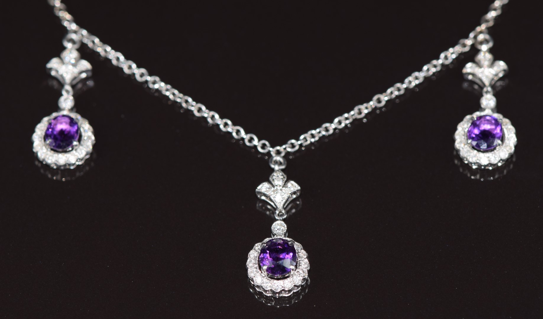 An 18ct white gold necklace with three drop sections set with oval cut amethysts and diamonds, 8.1g