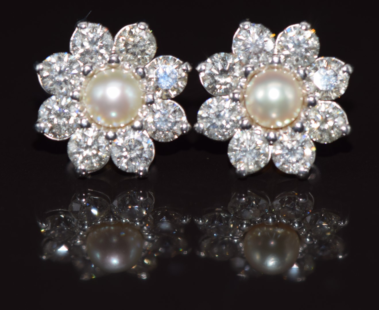 A pair of 18ct white gold earrings each set with a natural pearl measuring 5.3mm surrounded by eight