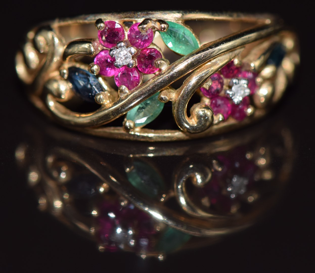 A 9ct gold ring set with diamonds, emeralds, sapphires and rubies in a floral pierced design, 2.