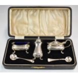 Cased George V hallmarked silver three piece cruet set with blue glass liner to the salt, together