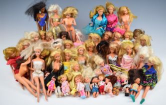 Fifty Mattel Barbie dolls of various ages including siblings, most dressed in original clothing.