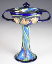 Moorcroft pottery twin handled stem cup and cover decorated with flowers on a blue ground, 2004,
