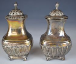 Pair of Victorian hallmarked silver peppers with reeded lower bodies, raised on four ball feet,