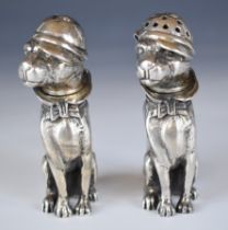Pair of novelty silver peppers formed as seated dogs in collared outfits with caps, marked 925 to