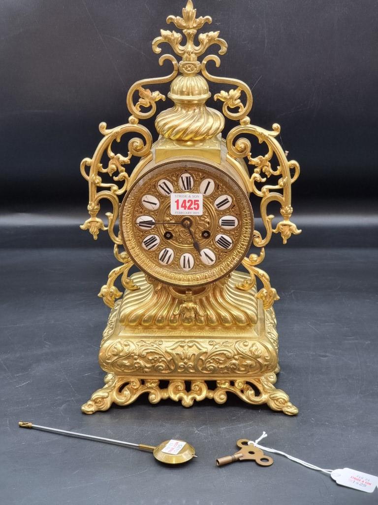 A brass mantel clock, with enamel chapter ring, 41.5cm high, with pendulum and winding key.