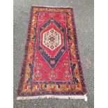 A Persian red ground rug, 227 x 113cm.