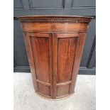 A George III mahogany and inlaid bowfront hanging corner cupboard, 119 x 78cm.