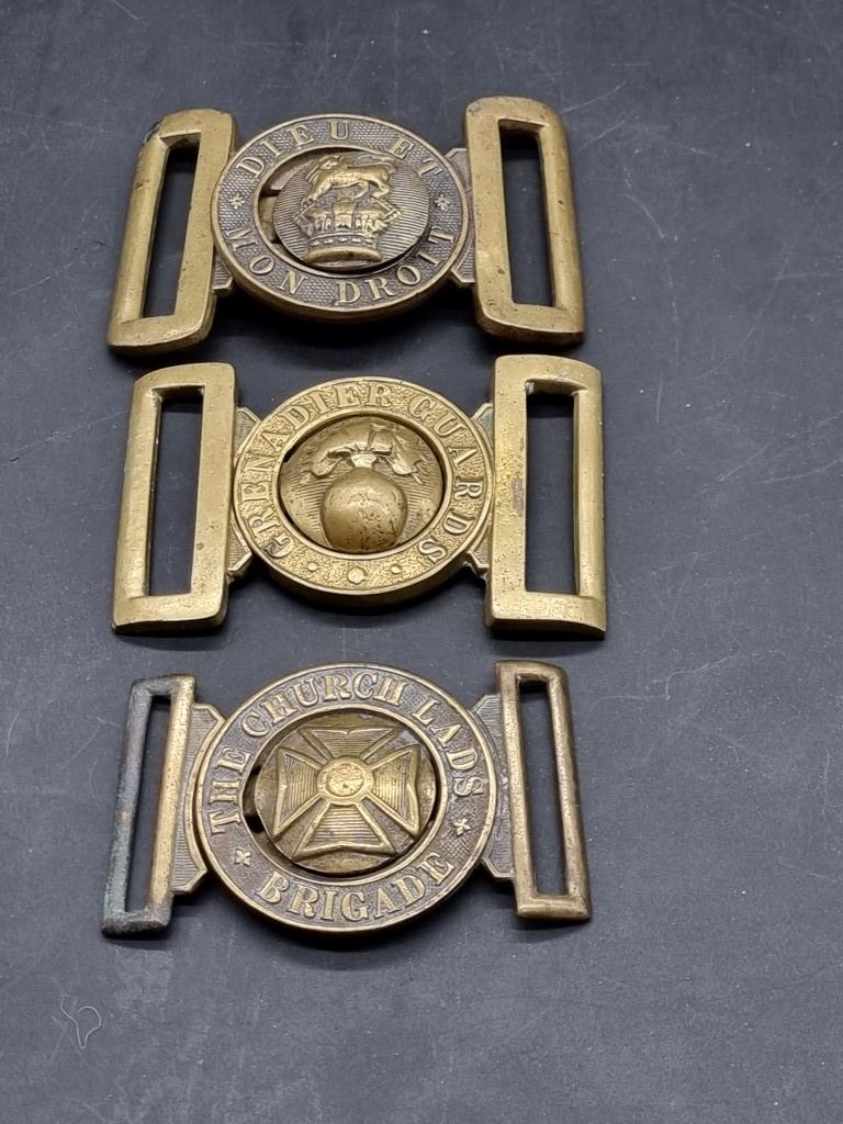 Three brass military belt buckles.