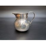 A silver milk jug by Vander & Hedges, London 1918, engraved crest, 11cm high, 347g.