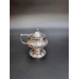 An antique silver mustard pot, having later floral embossed decoration, 9.5cm high; together with