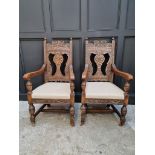 A pair of late Victorian carved oak open armchairs, with studded cream leather seats.