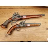 Two reproduction flintlock pistols.