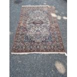 A Persian rug, having central floral cartouche, on cream ground with floral borders, 210 x 135cm.