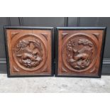 A pair of carved oak relief panels, of a dog and fox, in ebonized frames, the whole 57 x 53cm.