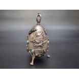 An Imperial Russian and gem set white metal novelty hunting egg, having repousse decoration of