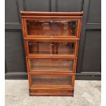 A good mahogany and crossbanded four tier sectional bookcase, with apron drawer and bevelled glass