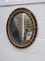 A Georgian Irish ebonized and parcel gilt framed oval wall mirror, 56.5 x 46.5cm.
