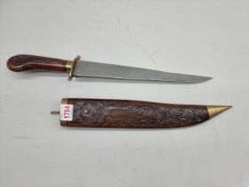 An Indian dagger and brass mounted carved wood sheath, the blade 30cm.