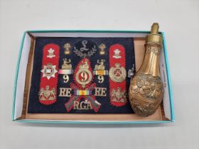 A display of World War I military badges; together with a copper powder flask.