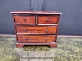 A miniature hardwood chest of drawers, 24cm high x 28.5cm wide x 15cm deep.