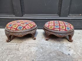 A pair of Victorian carved walnut and upholstered circular footstools.