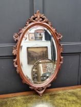 A carved walnut framed oval wall mirror, 90 x 54.5cm.