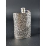 An Indian white metal hip flask, having chased floral decoration, 14cm high.