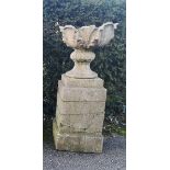 A composition stone urn on pedestal, possibly by Austin & Seeley