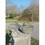 A pair of lidded composition stone urns