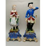 Man and Woman in old continental dress on blue and gilt base 27cm and 28cm