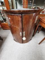 A Georgian mahogany bow fronted corner cupboard