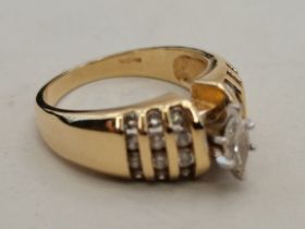 A ring marked 14k with central raised oblong diamo