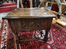 A carved oak stool with opening lid and carved gentleman decoration