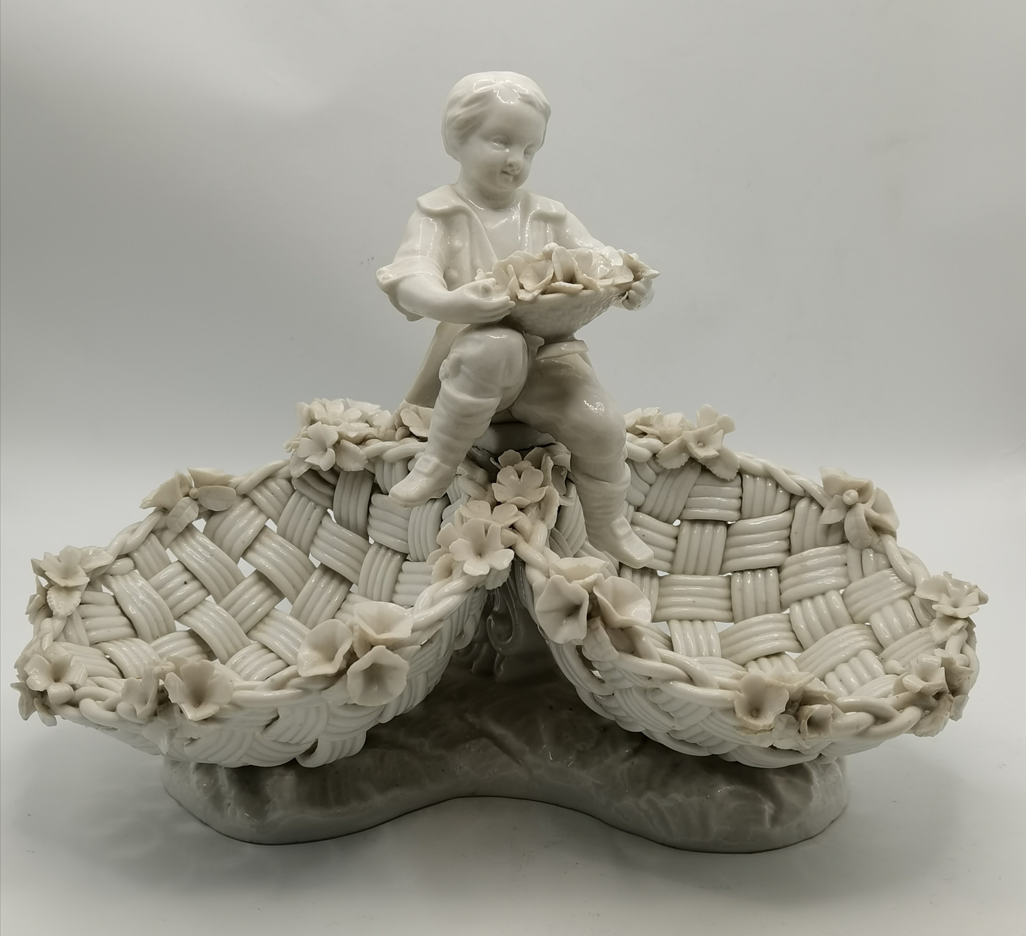 A Meissen creamware style figure of a boy with flo