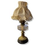 A VICTORIAN BRASS AND GLASS OIL LAMP Having a clear glass well and classical form, brass column