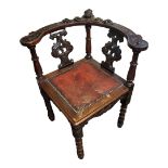 A LATE 19TH CENTURY HEAVILY CARVED MAHOGANY CORNER CHAIR Facial masks, mythical beasts foliage,