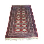 A BOKHARA WOOL RUG Having sixteen geometric form motifs to central field within eleven running