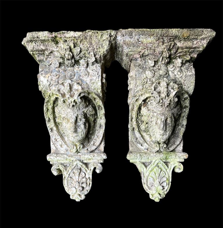 A PAIR OF CAST STONE CORBELS Figured with facial masks and foliage. (length 46cm) Condition: