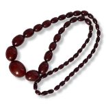 A VICTORIAN CHERRY AMBER NECKLACE Having a row of graduated oval beads of plain form. (approx 39cm),