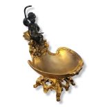 A GILT BRONZE ROCOCO DESIGN FIGURAL SALT FORMED AS CUPID Seated on a large shell and pierced
