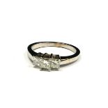 A 14CT WHITE GOLD AND DIAMOND THREE STONE RING The row of three Princess cut stones in a stepped