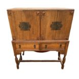 AN EARLY 20TH CENTURY OAK CABINET ON STAND With four doors above two drawers fitted with brass