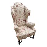 A WILLIAM AND MARY STYLE WING ARMCHAIR With scroll back and arms, shaped apron, upholstered in a