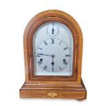 A CONTINENTAL MAHOGANY QUARTER STRIKING MANTEL CLOCK Having an arch form case with inlaid